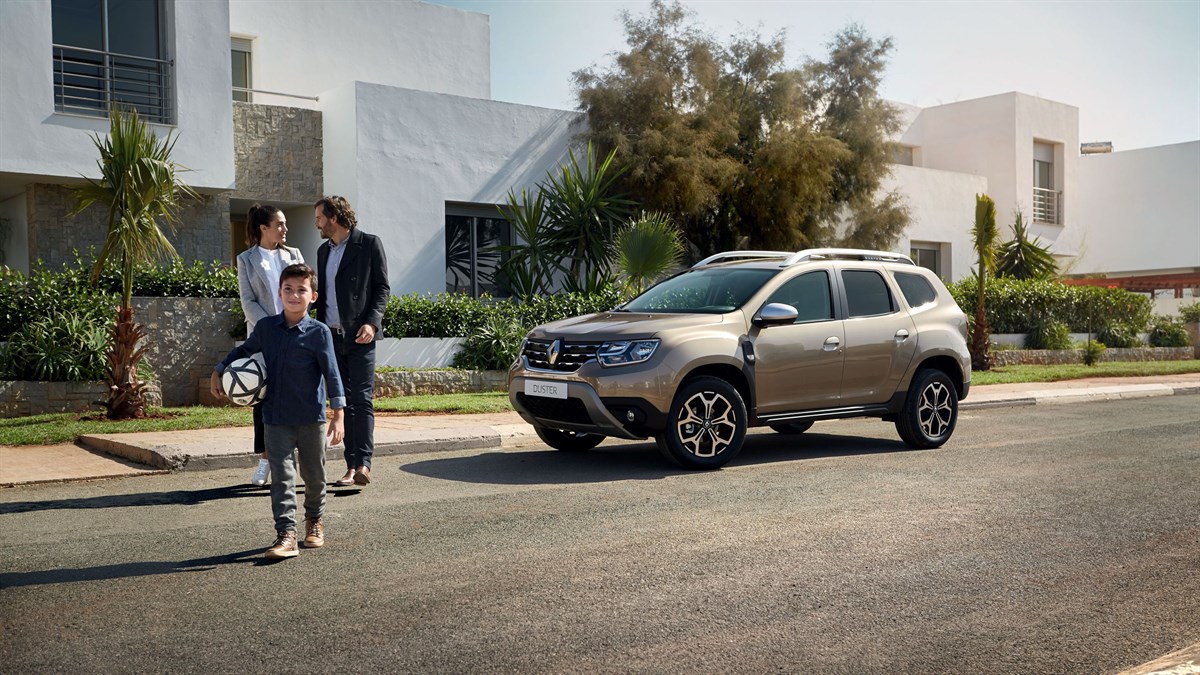 A couple and child with a football are standing in front of the All-New Renault Duster