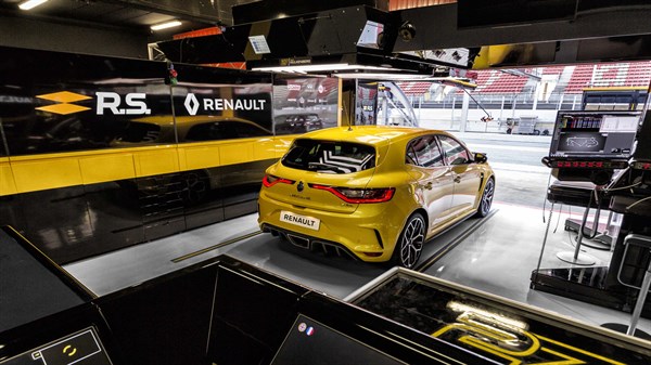 A back corner view of the yellow-colored Renault MEGANE R.S. shown inside its racing garage
